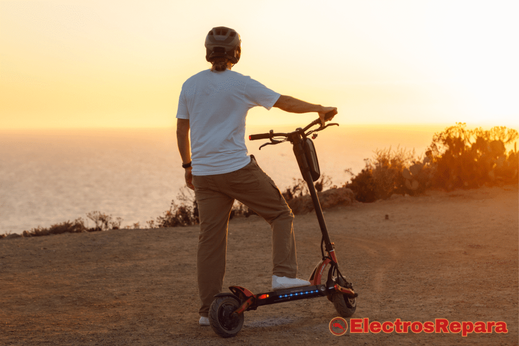 La imagen muestra a una persona con un patinete eléctrico observando el atardecer sobre el mar, transmitiendo una sensación de libertad y movilidad.