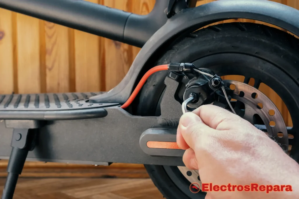 Una persona realizando mantenimiento preventivo en los frenos de un patinete eléctrico, limpiando las pinzas y el disco