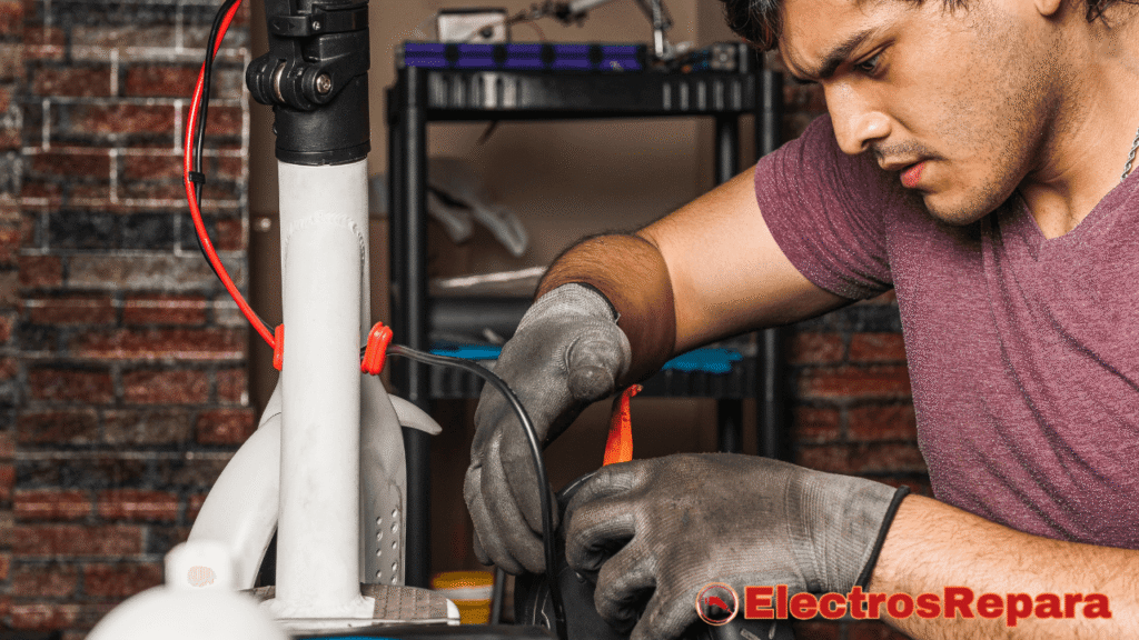 un hombre con guantes grises trabajando en la parte inferior de un patinete eléctrico blanco. Está manipulando unos cables, lo que sugiere una posible reparación o diagnóstico de un problema eléctrico. La concentración en su rostro y la manipulación de los cables podrían estar relacionados con la investigación de por qué el patinete eléctrico pierde potencia. El fondo muestra una pared de ladrillo rojizo y una estantería con objetos no claramente definidos. 