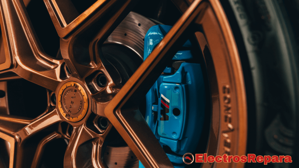 La imagen es un primer plano de una rueda de coche, donde se destaca el sistema de frenos. Se observa un disco de freno perforado y, lo que es más prominente, una pinza de freno de color azul brillante