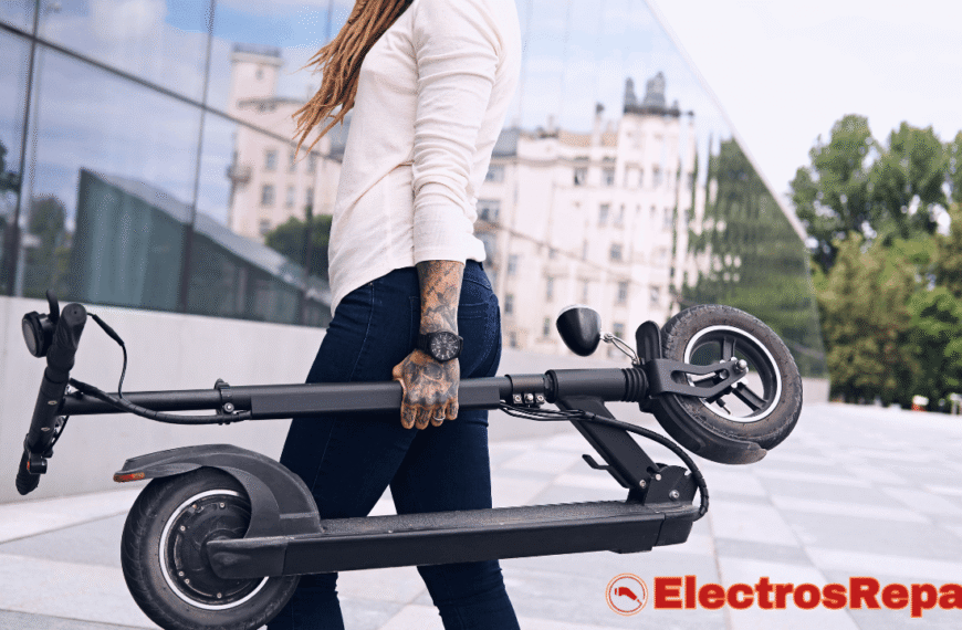 La imagen muestra a una persona (posiblemente una mujer con rastas y tatuajes en el brazo) caminando y llevando un patinete eléctrico plegado. El patinete es de color oscuro y parece estar en buen estado. El fondo sugiere un entorno urbano moderno con edificios de cristal y árboles. Aunque no es visible en la imagen, el Controlador de Patinete Eléctrico es un componente esencial de este tipo de vehículo, responsable de gestionar la potencia y las funciones del patinete que la persona transporta.