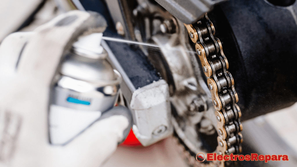 un proceso de lubricación de la cadena de tu bicicleta eléctrica. Una mano enguantada en blanco sostiene un bote de aerosol y aplica un lubricante directamente sobre la cadena. La cadena tiene un aspecto metálico brillante y está conectada al cassette y al motor de la bicicleta. Se puede ver claramente cómo el lubricante es rociado sobre los eslabones de la cadena. El fondo está ligeramente desenfocado, lo que dirige la atención hacia el proceso de lubricación de la cadena de tu bicicleta eléctrica.