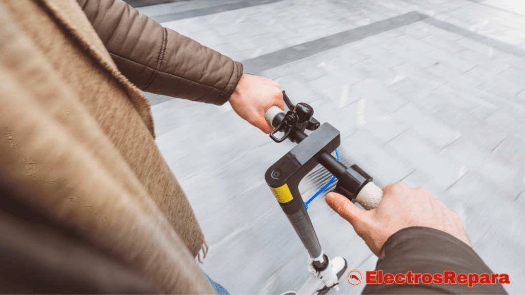 
La imagen muestra una perspectiva en primera persona de una persona conduciendo un patinete eléctrico. Las manos del conductor sujetan firmemente el manillar del patinete eléctrico, que es de color negro con detalles en azul brillante y una franja amarilla cerca de la base. El puño derecho es blanco o gris claro y tiene una textura. Se pueden ver los cables de freno y aceleración conectándose al manillar. El fondo consiste en un suelo urbano pavimentado y liso, borroso por el movimiento, que sugiere que el patinete está en marcha. 