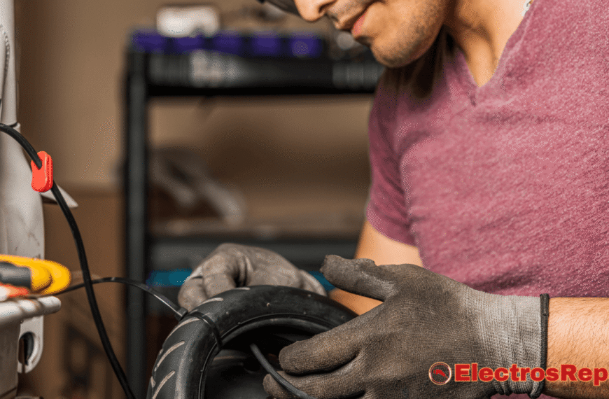 una persona con una camiseta de color vino y guantes de trabajo, manipulando lo que parece ser la rueda de un patinete eléctrico. Se observan cables eléctricos y herramientas en un entorno de taller.