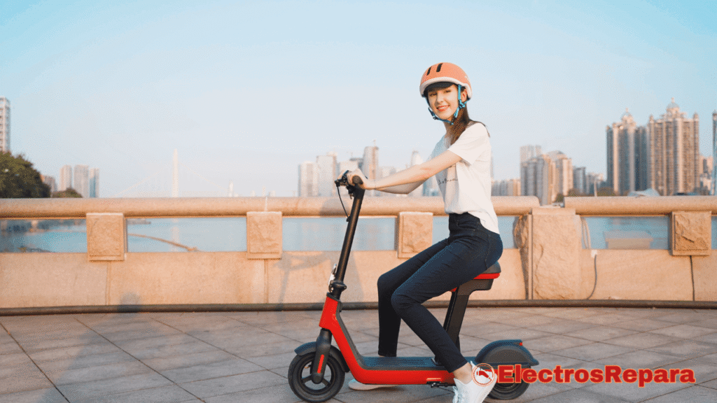 La imagen muestra a una joven con casco de seguridad que está sentada sobre un patinete eléctrico de color rojo y negro. El patinete tiene un asiento, lo que le da un aspecto similar a una calavera de bicicleta. La mujer está sonriendo y parece estar disfrutando de un paseo al aire libre, con un paisaje urbano de fondo. La foto sugiere la libertad y la practicidad del transporte personal eléctrico, resaltando la importancia de un buen mantenimiento del motor de patinete eléctrico para garantizar un rendimiento óptimo y una experiencia de uso segura.