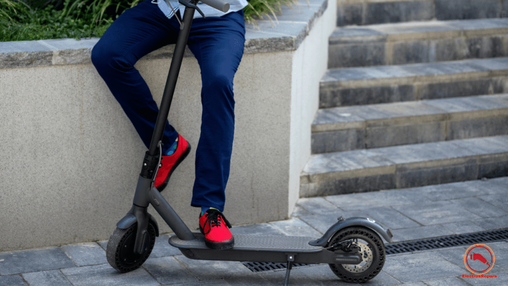 Una persona se encuentra sobre una superficie de piedra con un patinete eléctrico, conectado a la electricidad. La lubricación de las ruedas es crucial para su correcto funcionamiento y mantenimiento.